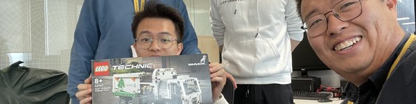 Four Year in Industry students smiling at the camera. One of them is holding a box of lego