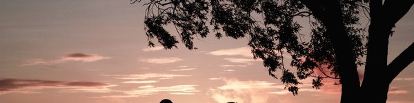 A couple sitting on camping chairs chatting whilst the sunsets